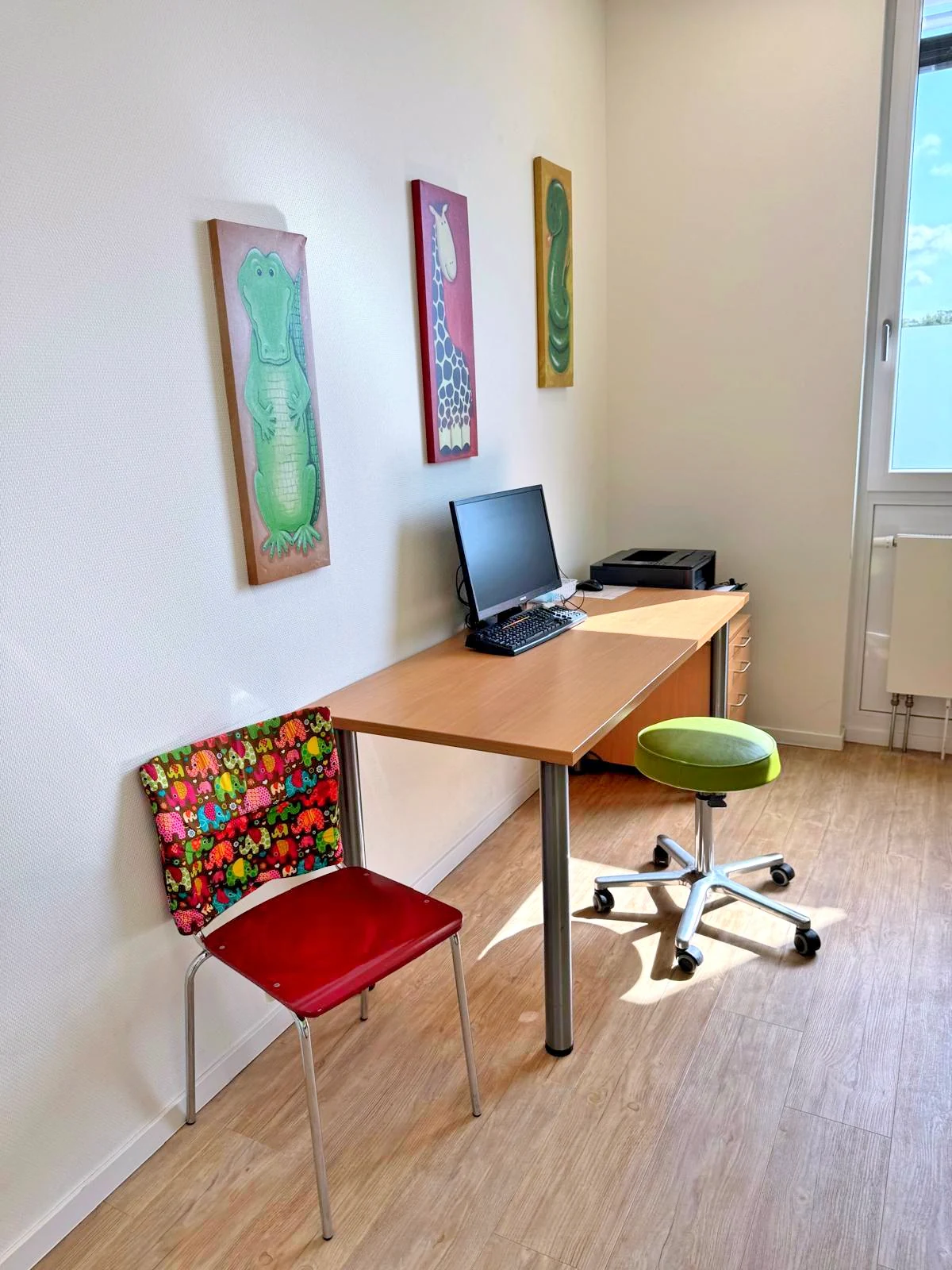 Sprechzimmer mit Tierbildern an der Wand und Arbeitsplatz am Fenster