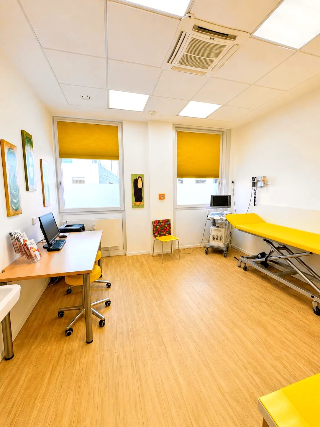 Helles Behandlungszimmer mit gelber Untersuchungsliege und Ultraschallgerät
