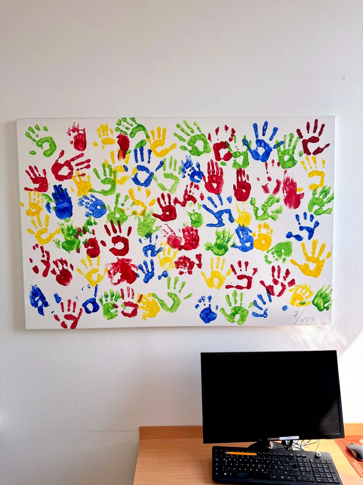 Leinwand mit bunten Kinderhandabdrücken an der Wand der Praxis